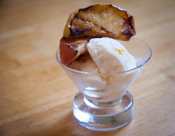 Grilled apple slices, sprinkled with cinnamon and sugar, over ice cream.